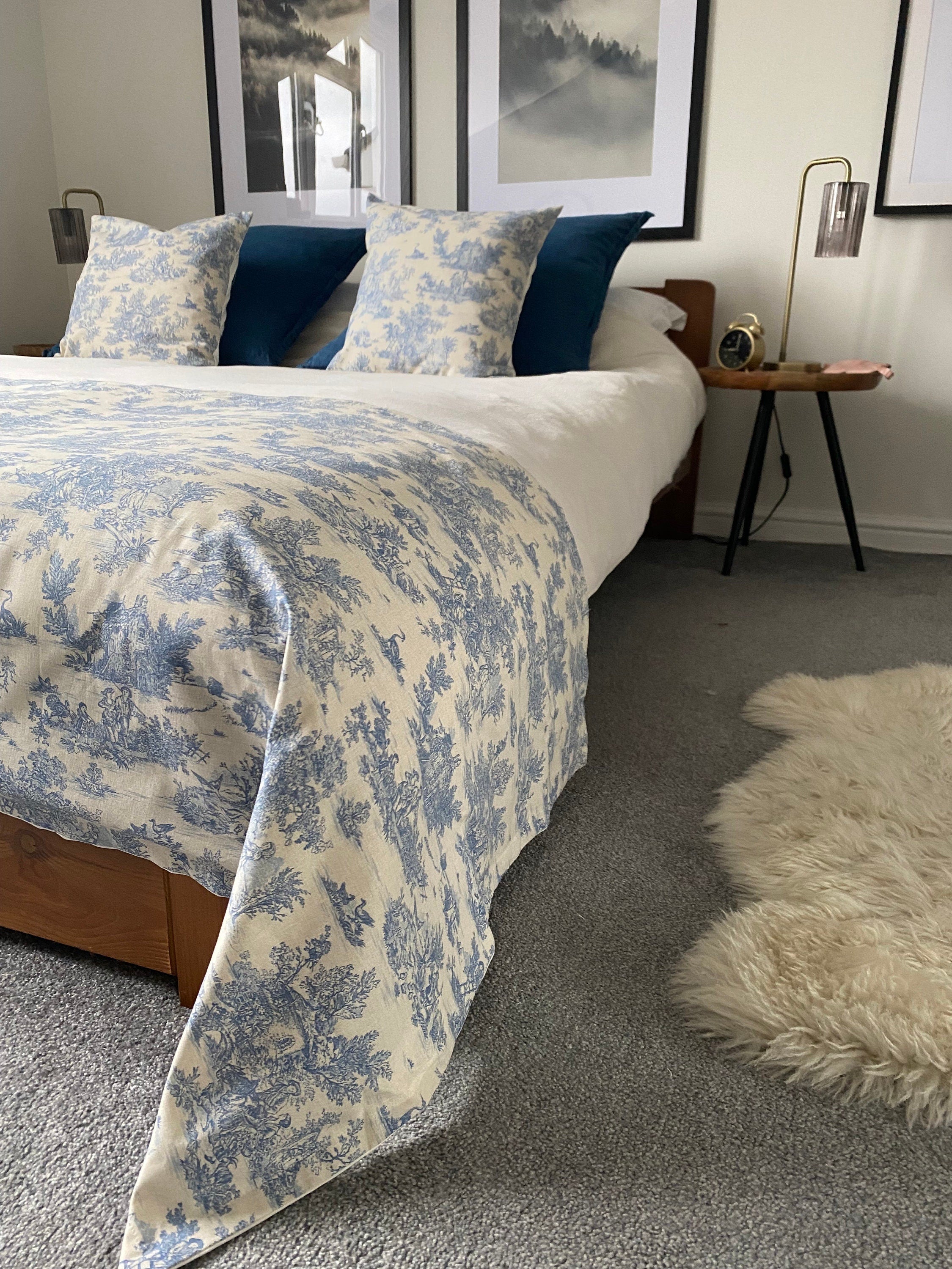 a blue toile de jouy bed scarf with matching cushions on a king size bed