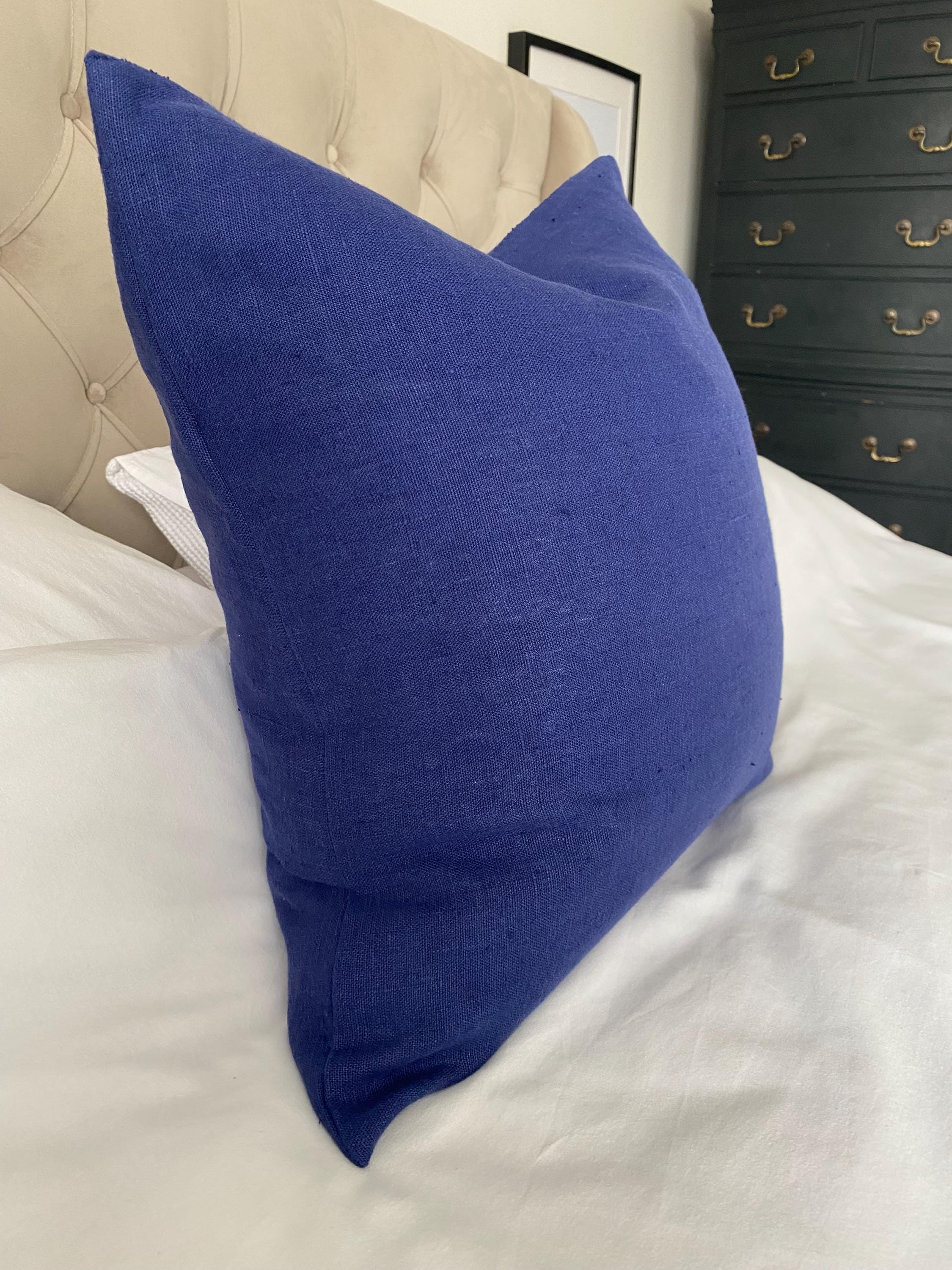 Royal Blue pillow on a bed with a dresser in the background