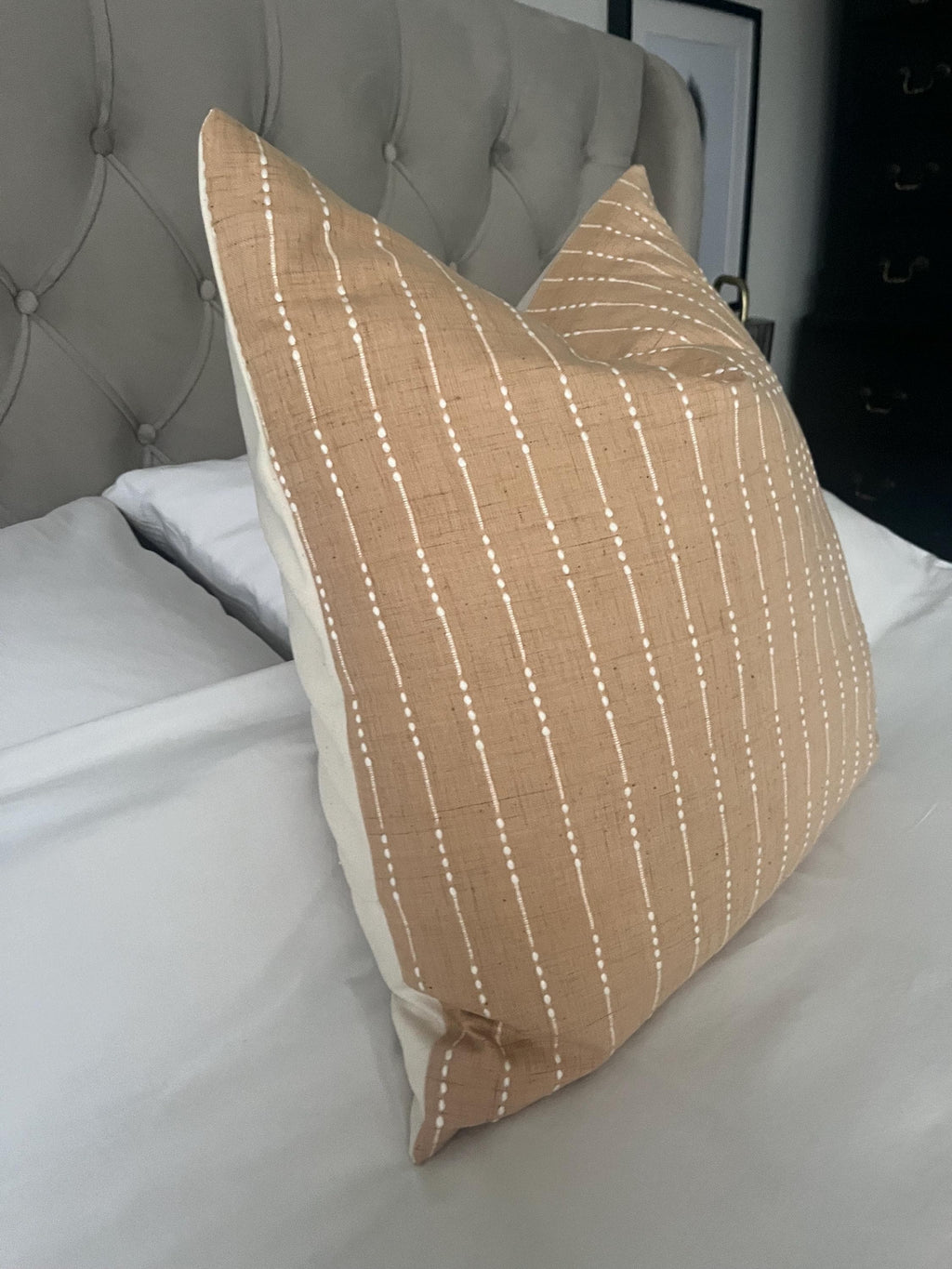 Handwoven beige cotton cushion cover with subtle vertical stripe pattern on bed