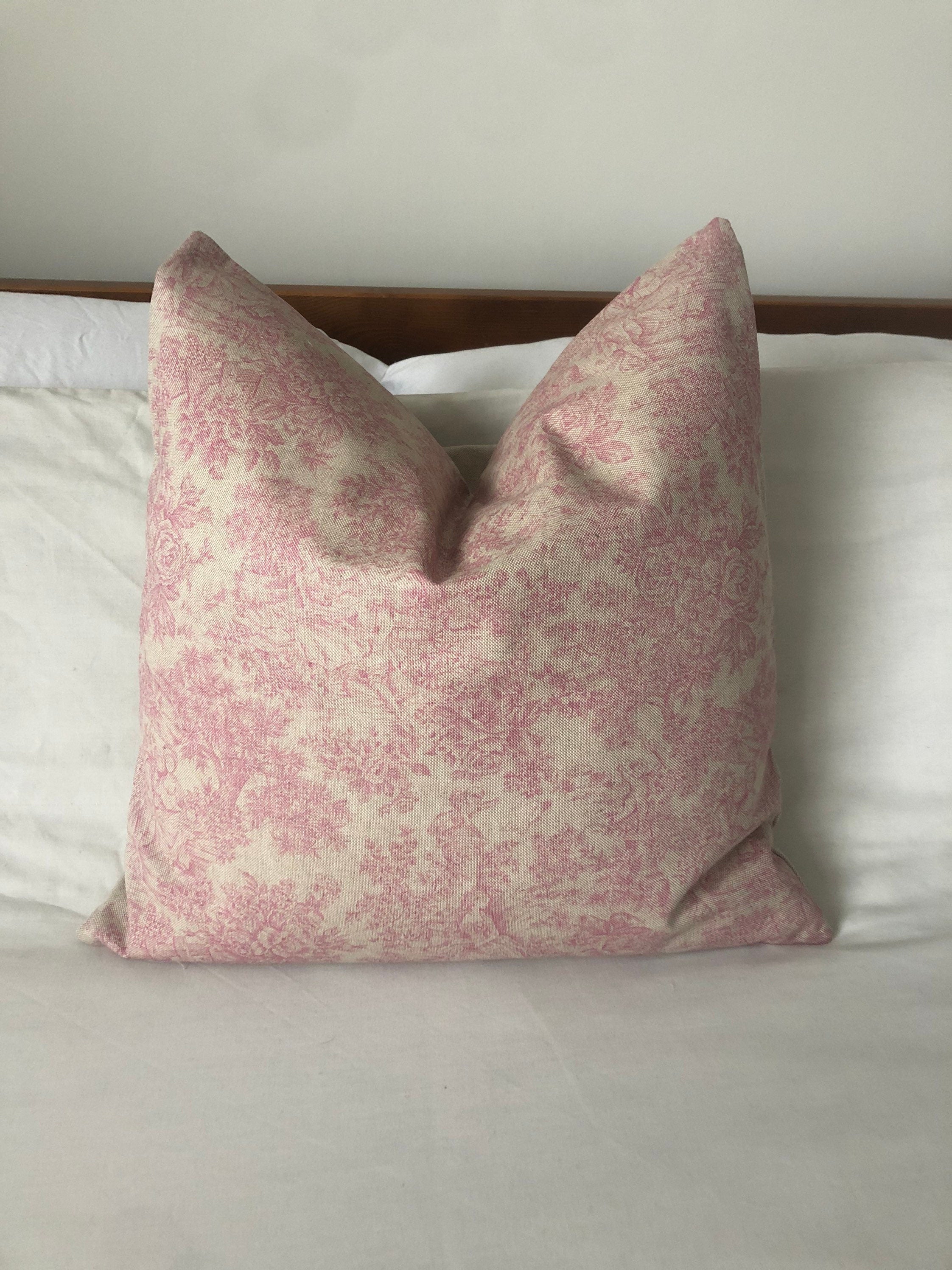 vintage Pink toile patterned pillow on a bed with a neutral background