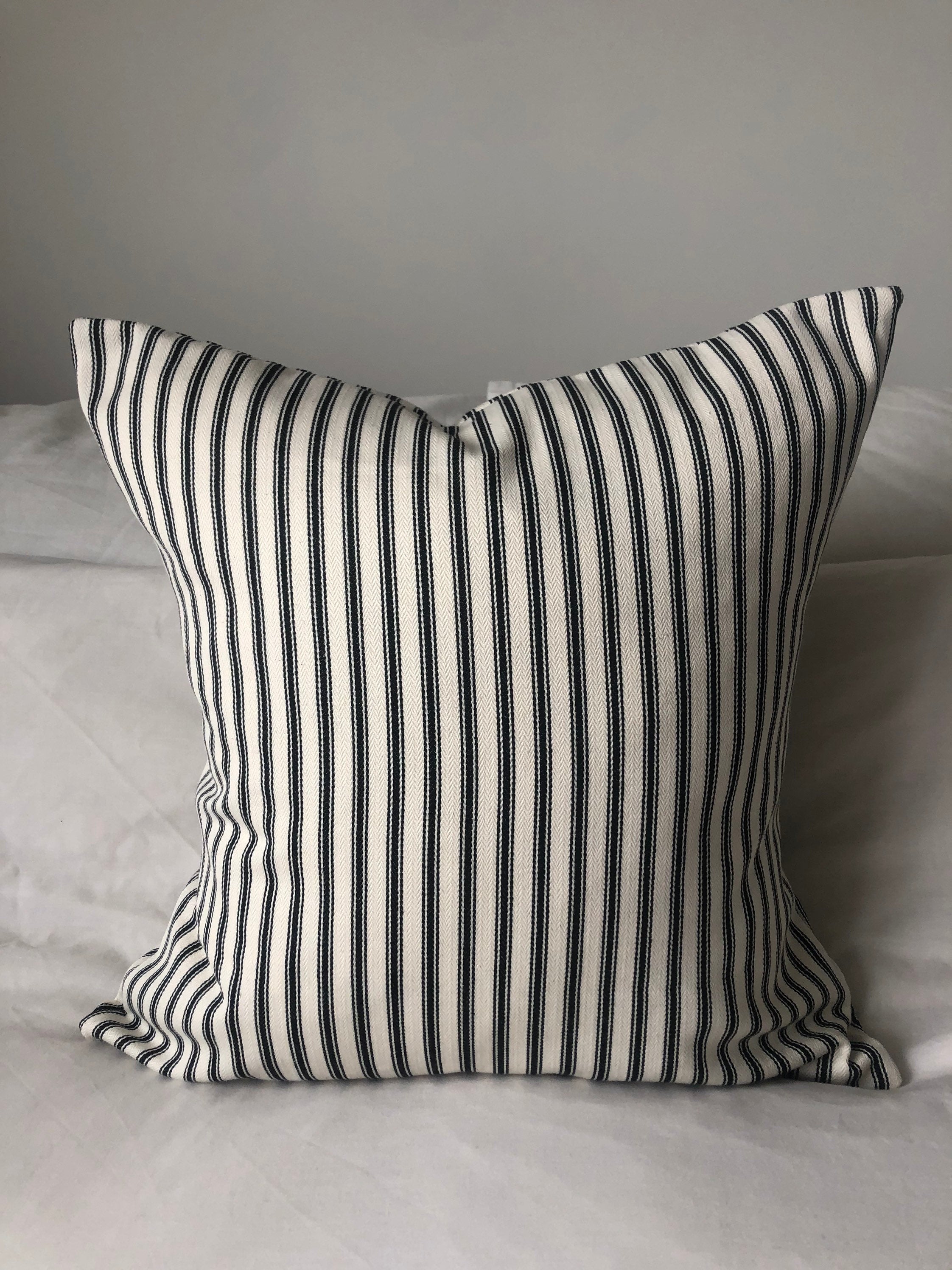 Striped black pillow on a bed with a neutral background