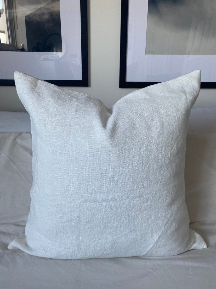 off white linen cushion on a white bed
