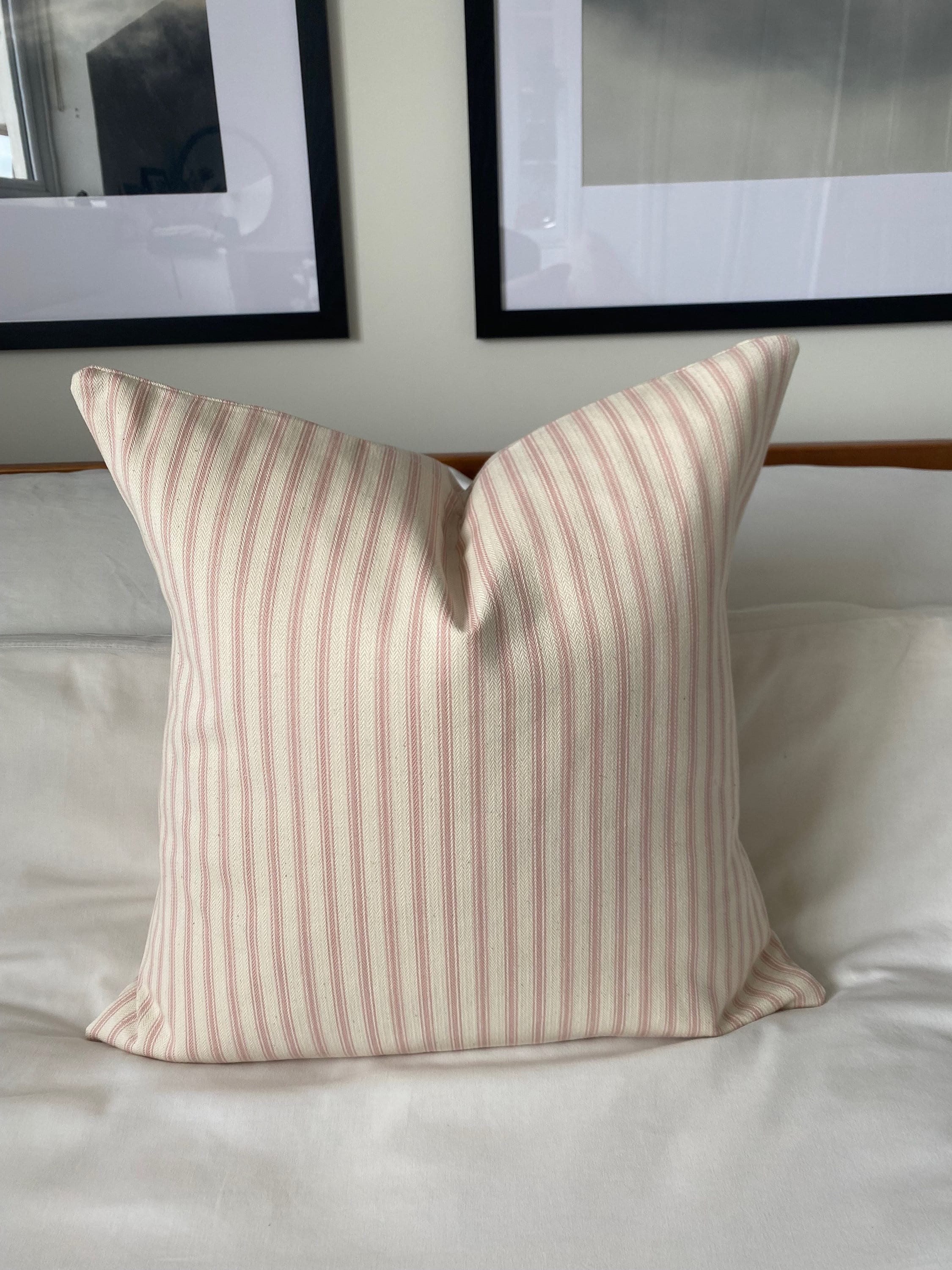 pink Striped pillow on a bed with framed pictures in the background