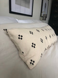 Beige pillow with black patterns on a bed in a bedroom setting