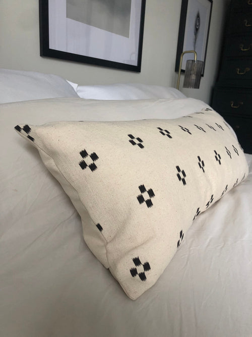 Beige pillow with black patterns on a bed in a bedroom setting