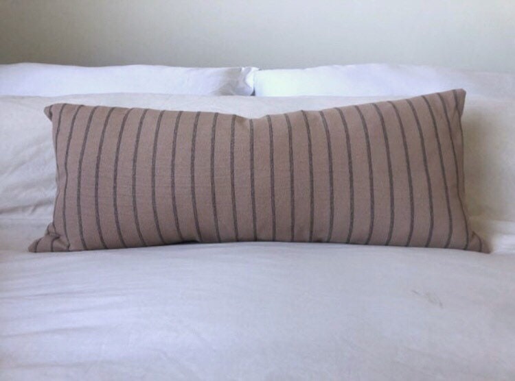 Striped brown and black pillow on a bed with white bedding