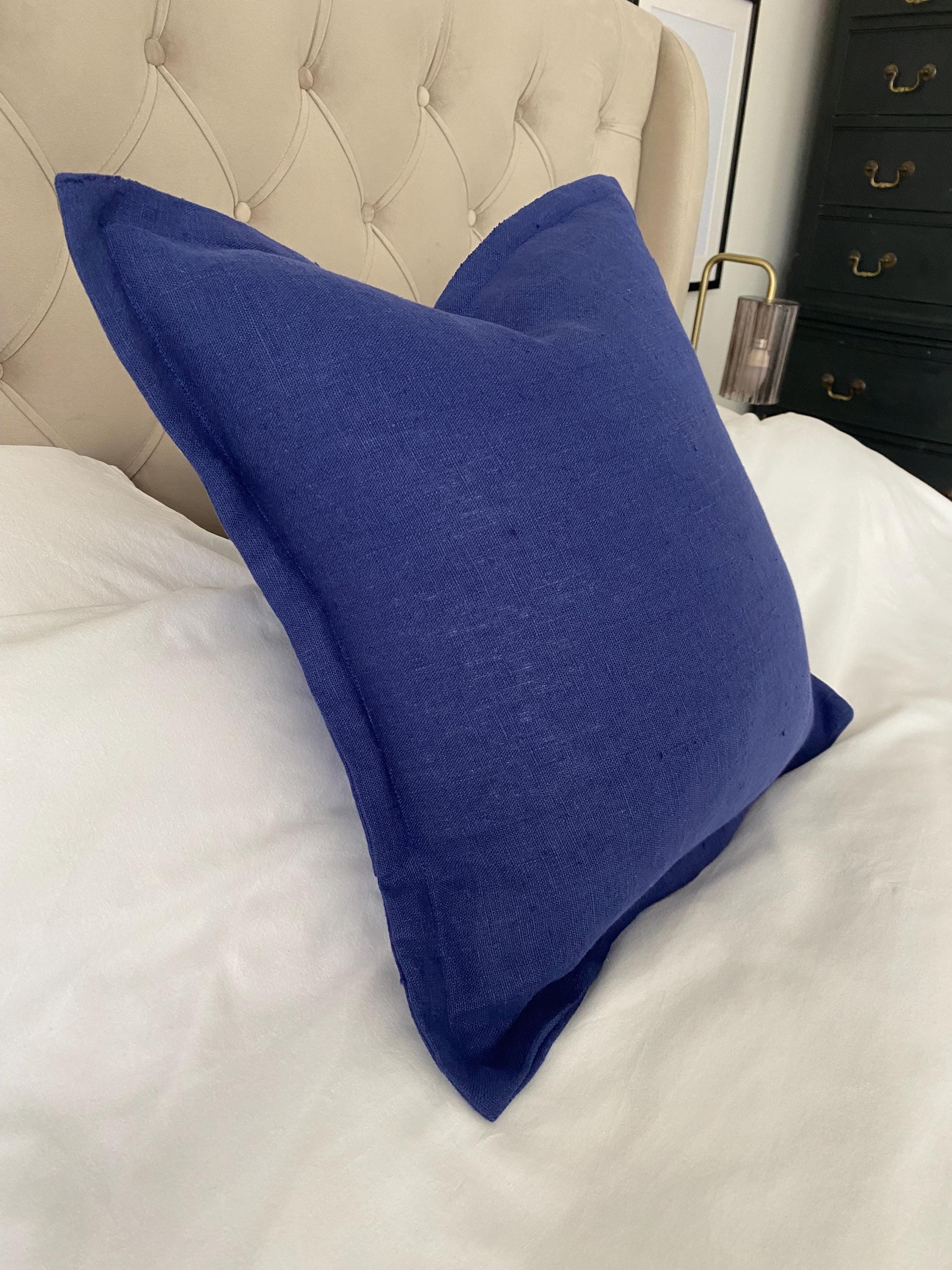 Royal Blue pillow, with flange edging on a bed with a tufted headboard and dresser in the background