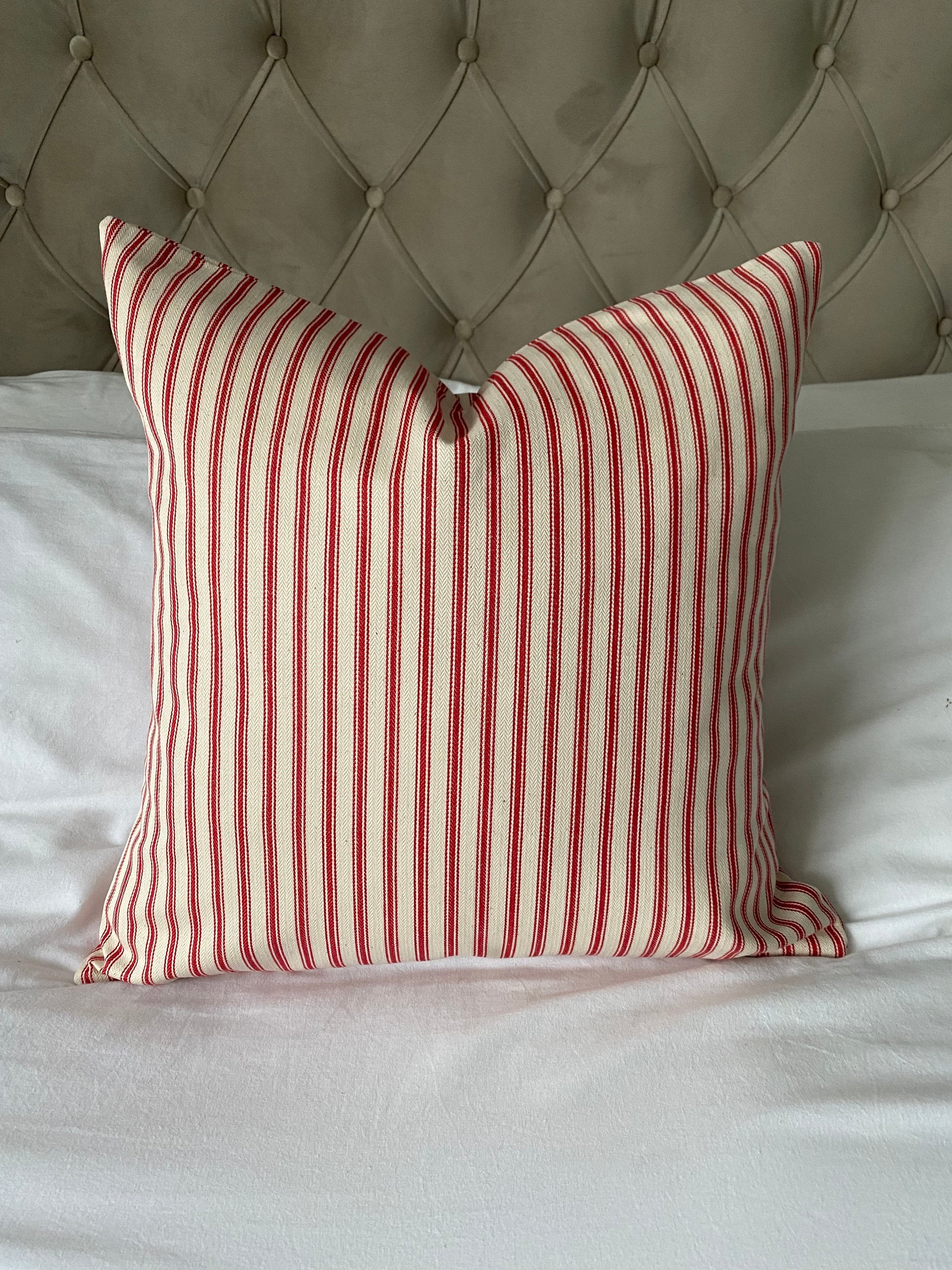 Red and white striped ticking cotton pillow on a whte bed