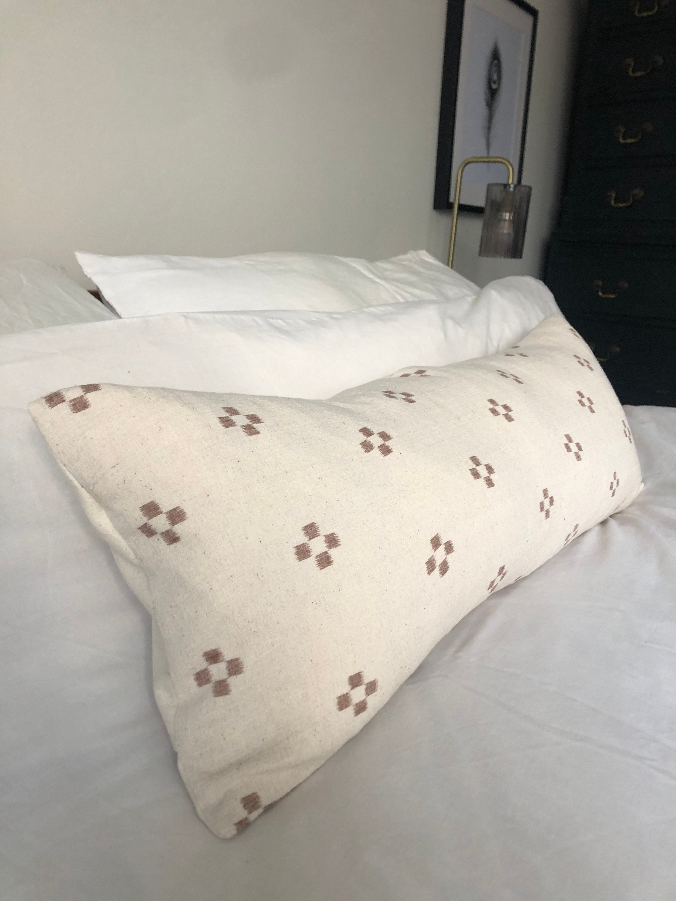 Decorative pillow with brown pattern on a bed in a bedroom setting.