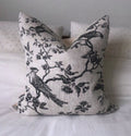 Decorative pillow with black floral and bird pattern on a light beige background