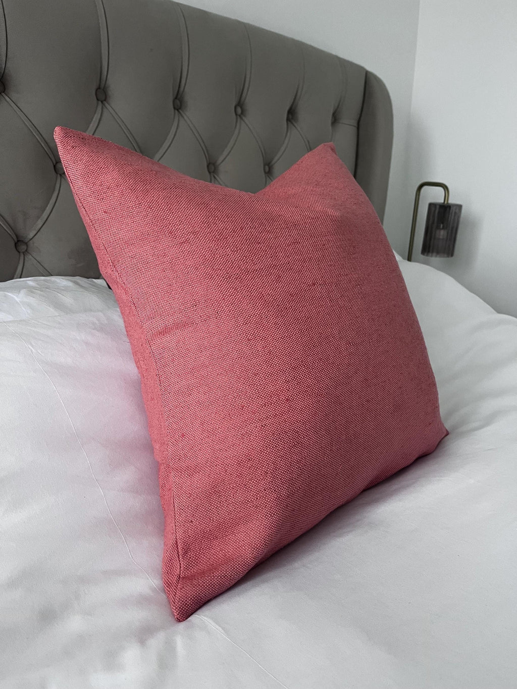 Pink pillow on a bed with a tufted headboard