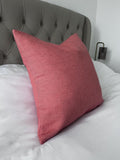 Pink pillow on a bed with a tufted headboard