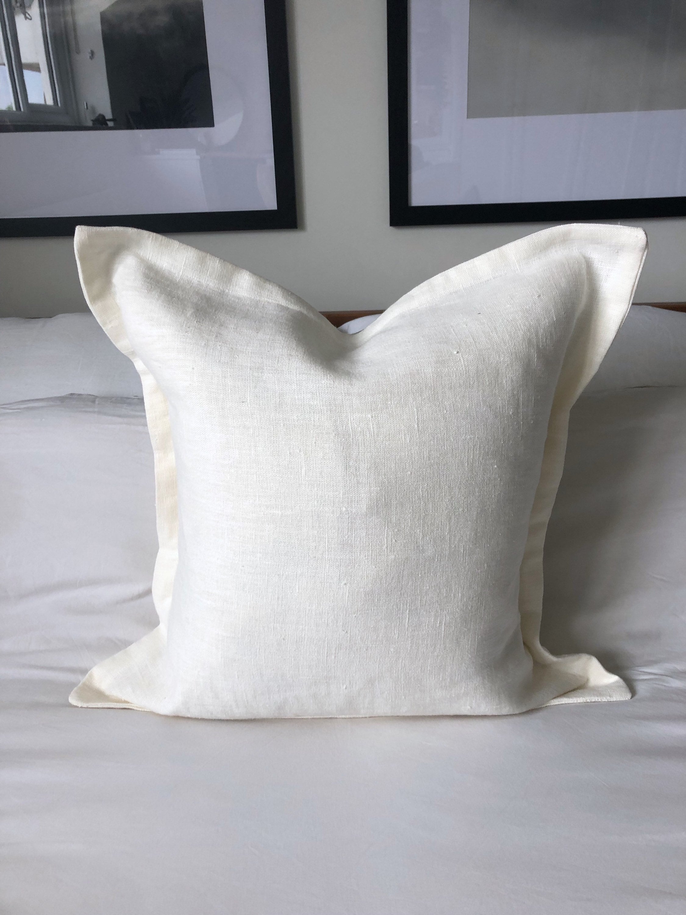 cream linen pillow with flange edging on a white bed
