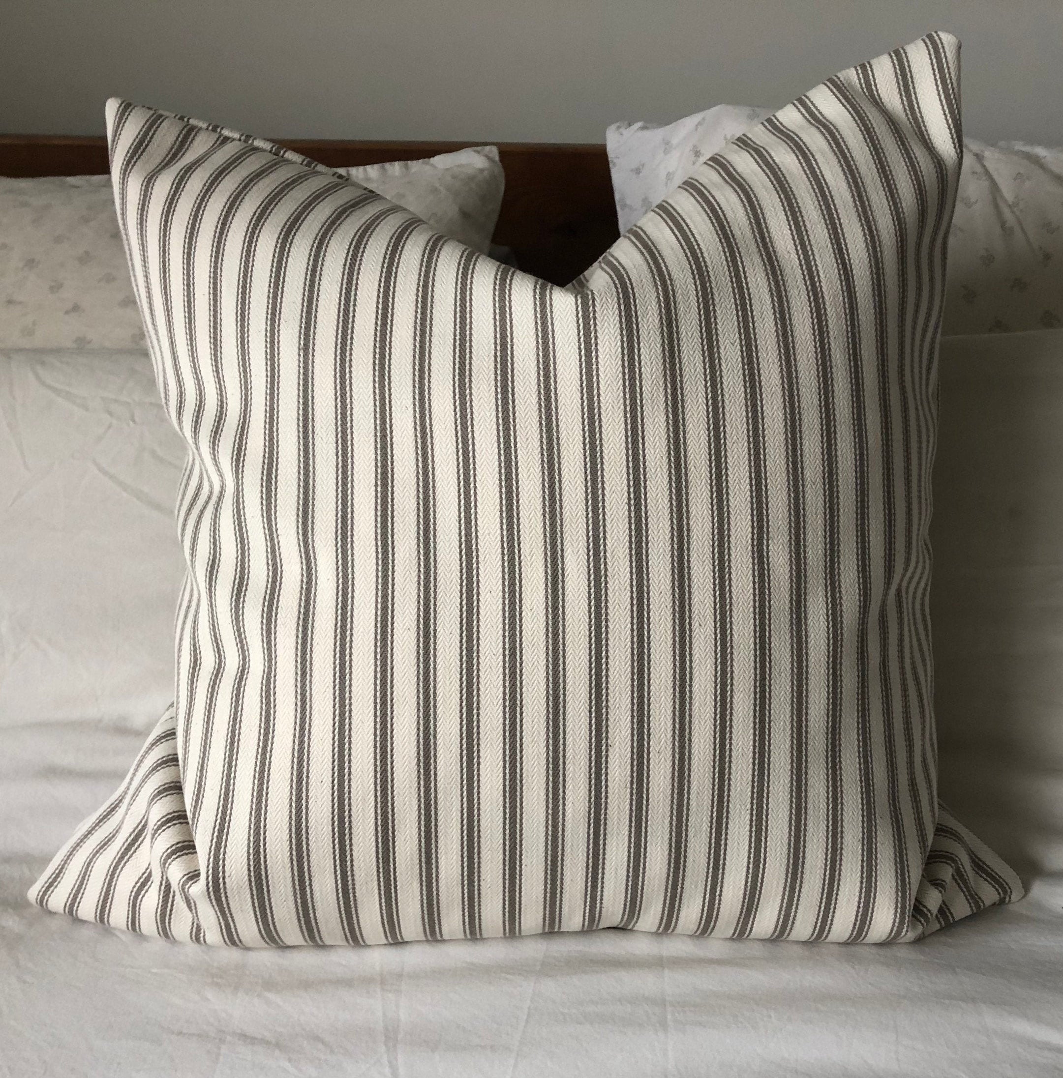 beige striped pillow on a white bed
