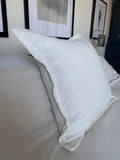 off white oxford edged pillow cover on a white bed
