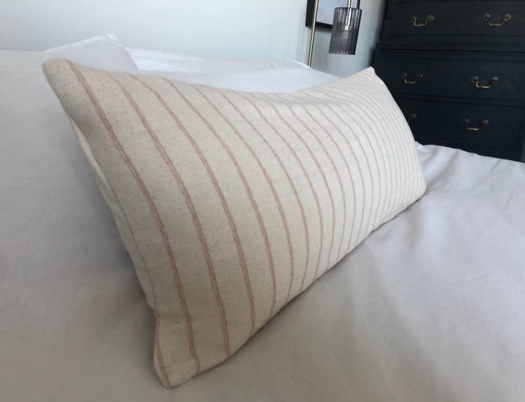 Beige and tan stripe pillow on a bed in a bedroom setting