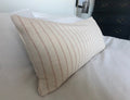 Beige and tan stripe pillow on a bed in a bedroom setting