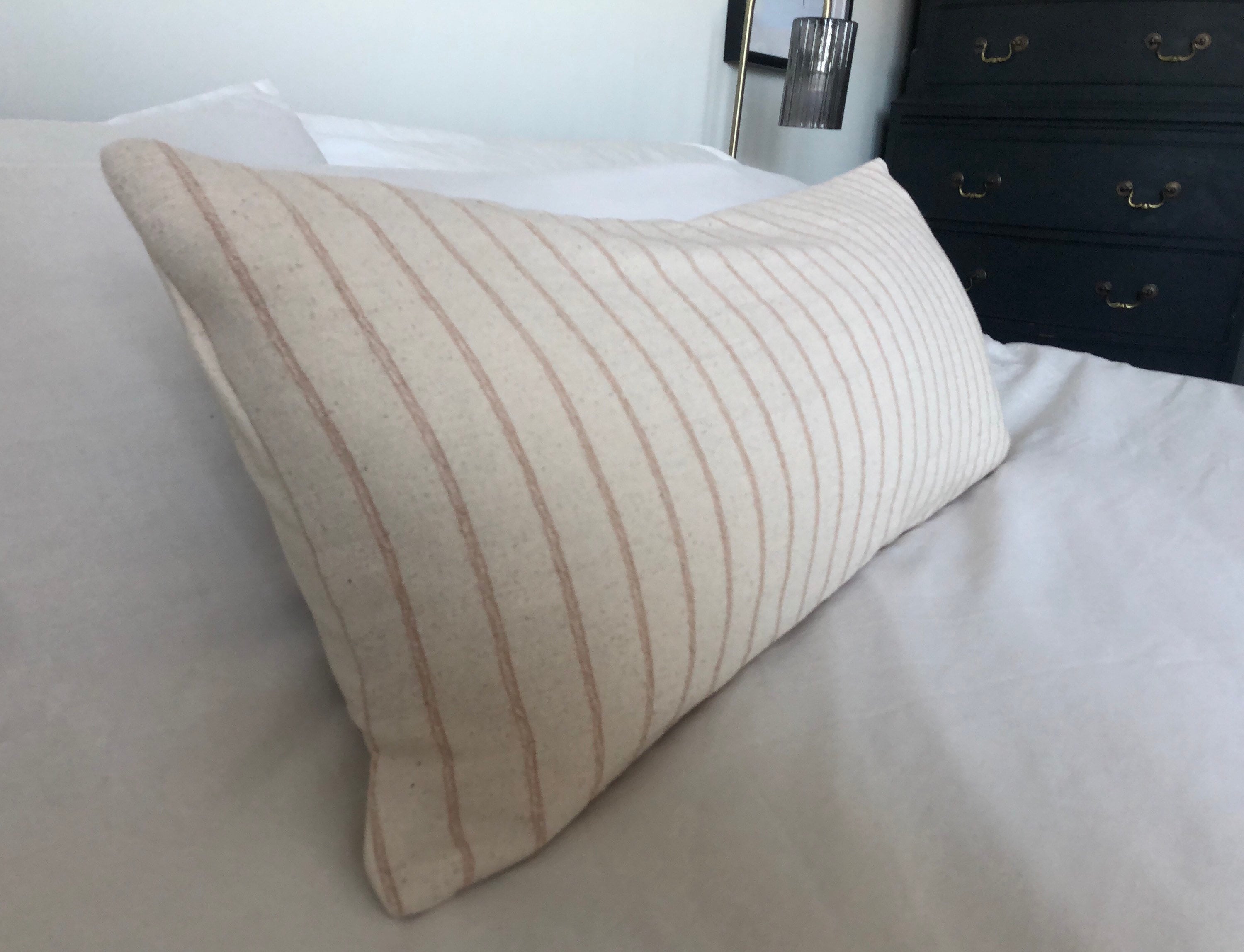 Beige and tan stripe pillow on a bed in a bedroom setting